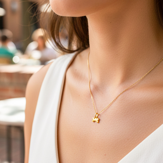 Cuello de modelo usando una cadena con un dije en forma de hueso en oro amarillo de 18 quilates de Joyería Caracas.