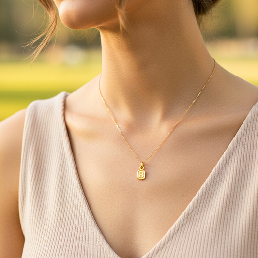 Cuello de modelo usando una cadena con un dije en forma de la letra B en oro amarillo de 18 quilates de Joyería Caracas.