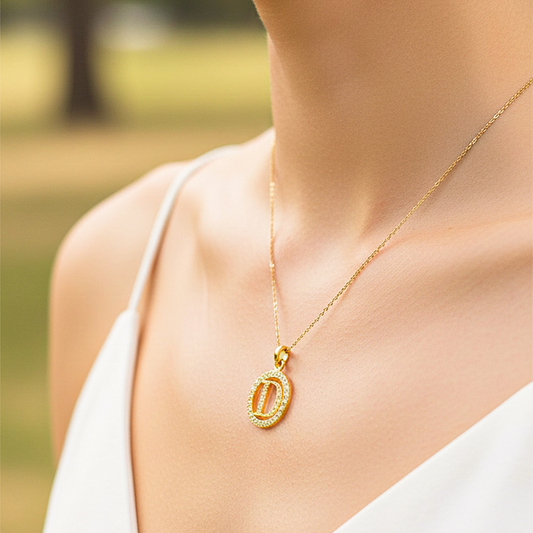Cuello de modelo usando una cadena con un dije de la letra D en oro amarillo de 18 quilates con cristales de Joyería Caracas.