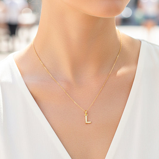 Cuello de modelo usando una cadena con un dije de la letra L en oro amarillo de 18 quilates con cristales de Joyería Caracas.