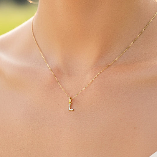 Cuello de modelo usando una cadena con un dije de la letra L en oro amarillo de 18 quilates con cristales de Joyería Caracas.