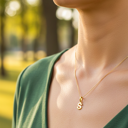 Cuello de modelo usando una cadena con un dije en forma de la letra S en oro amarillo de 18 quilates de Joyería Caracas.