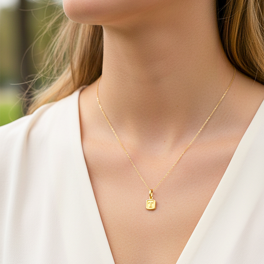Cuello de modelo usando una cadena con un dije de la letra T en oro amarillo de 18 quilates de Joyería Caracas.