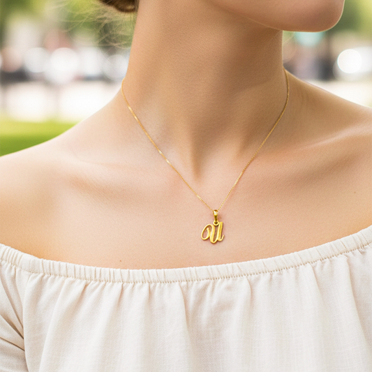 Cuello de modelo usando una cadena con un dije de la letra U cursiva en oro amarillo de 18 quilates de Joyería Caracas.
