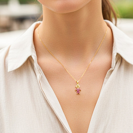 Cuello de modelo usando una cadena con un dije en forma de Mamá en oro amarillo de 18 quilates con cristales rosas de Joyería Caracas.