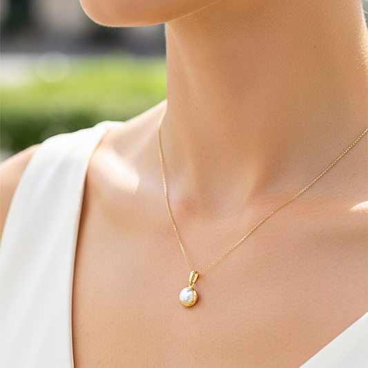 Cuello de modelo usando una cadena con un dije en oro amarillo de 18 quilates con media perla de Joyería Caracas.