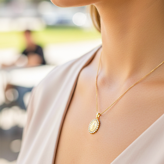 Cuello de modelo usando una cadena con un dije de la Virgen Milagrosa en oro amarillo de 18 quilates con cristales de Joyería Caracas.