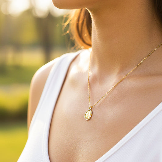 Cuello de modelo usando una cadena con un dije de la Virgen Milagrosa en oro amarillo de 18 quilates con cristales de Joyería Caracas.