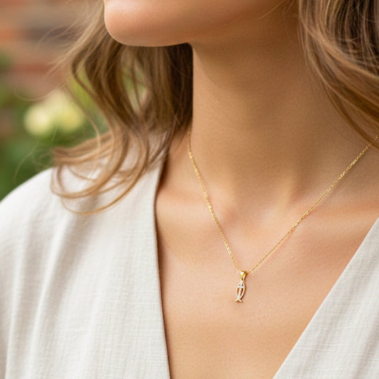 Cuello de modelo usando una cadena con un dije en forma de gota con cruz en oro amarillo de 18 quilates y cristales de Joyería Caracas.