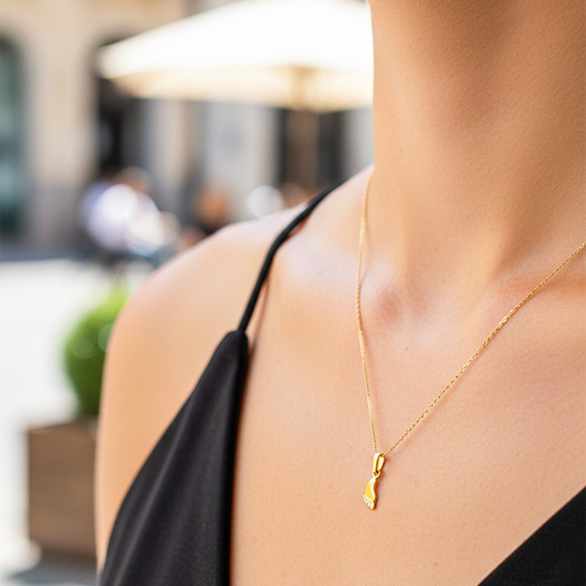 Cuello de modelo usando una cadena con un dije en forma de pie descalzo en oro amarillo de 18 quilates de Joyería Caracas.