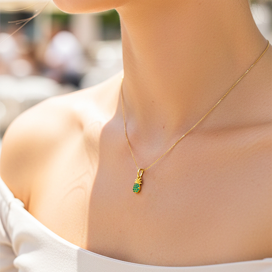 Cuello de modelo usando una cadena con un dije en forma de piña en oro amarillo de 18 quilates con cristales de Joyería Caracas.