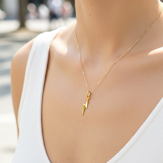Cuello de modelo usando una cadena con un dije en forma de rayo liso en oro amarillo de 18 quilates de Joyería Caracas.