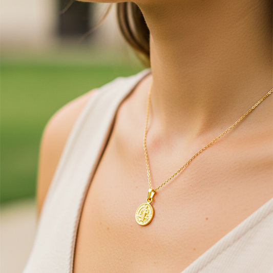 Cuello de modelo usando una cadena con un dije en forma de San Benito en oro amarillo de 18 quilates de Joyería Caracas.