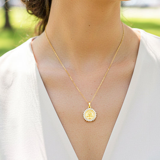 Cuello de modelo usando una cadena con un dije en forma de San Benito en oro amarillo de 18 quilates con cristales de Joyería Caracas.