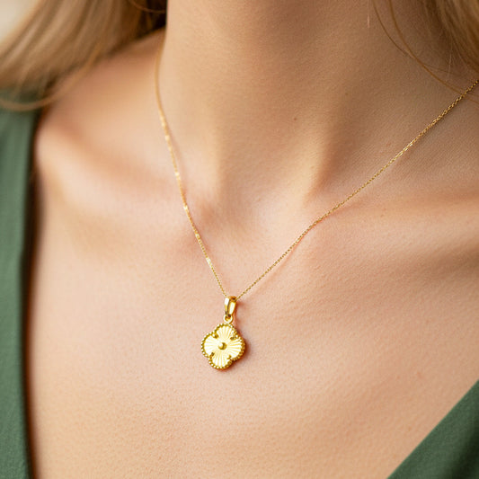 Cuello de modelo usando una cadena con un dije en forma de trébol diamantado en oro amarillo de 18 quilates de Joyería Caracas.