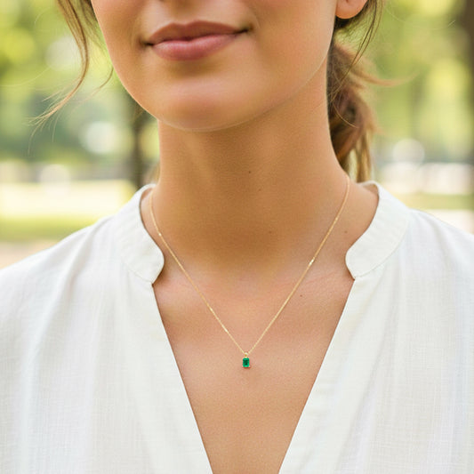 Cuello de modelo usando una cadena con un dije en oro amarillo de 18 quilates con Esmeralda rectangular de Joyería Caracas.