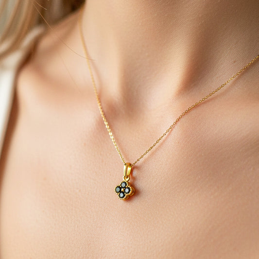 Cuello de modelo usando una cadena con un dije de trébol en oro amarillo de 18 quilates con cristales negros de Joyería Caracas.