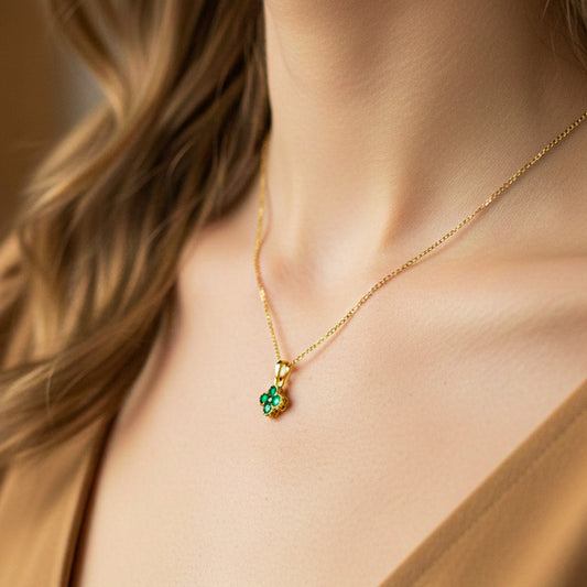 Cuello de modelo usando una cadena con un dije de trébol en oro amarillo de 18 quilates con cristales verdes de Joyería Caracas.