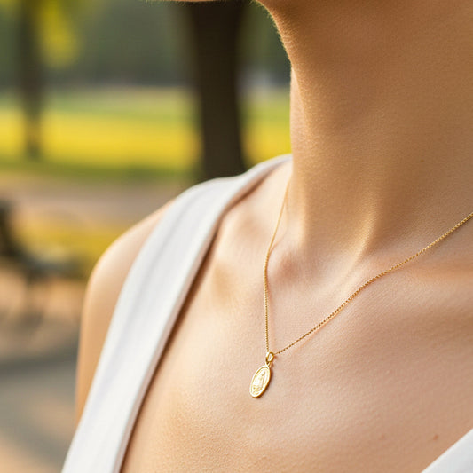 Cuello de modelo usando una cadena con un dije ovalado de la Virgen de la Caridad en oro amarillo de 18 quilates de Joyería Caracas.