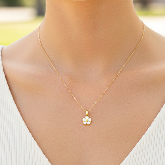 Cuello de modelo usando una cadena con un dije en forma de flor en oro amarillo de 18 quilates con Nacar de Joyería Caracas.