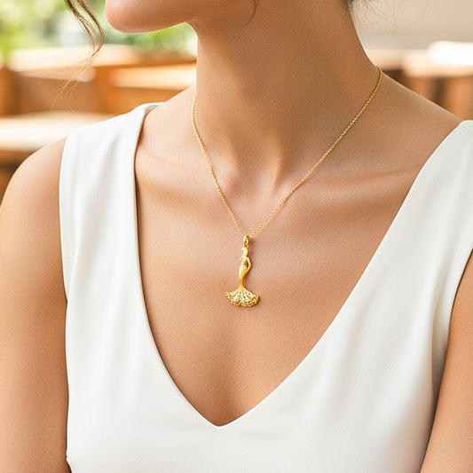 Cuello de modelo usando una cadena con un dije de mujer con vestido en oro amarillo de 18 quilates de Joyería Caracas.