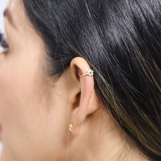 Oreja de mujer con earcuff en forma de flor en oro amarillo de 18 quilates con cristales de color blanco y verde, hecho en Joyería Caracas.