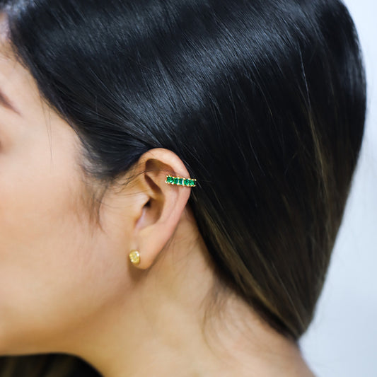 Oreja de mujer con earcuff en oro amarillo de 18 quilates con cristales de color verde, hecho en Joyería Caracas.