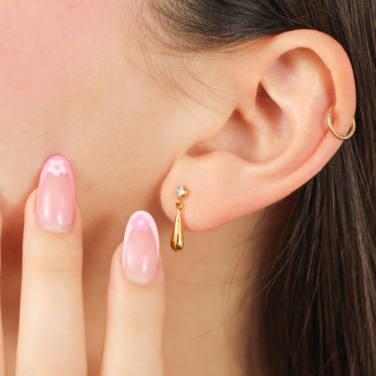 Oreja de mujer con topito en forma de gota en oro amarillo de 18 quilates con cristal de color verde, hechos en Joyería Caracas.