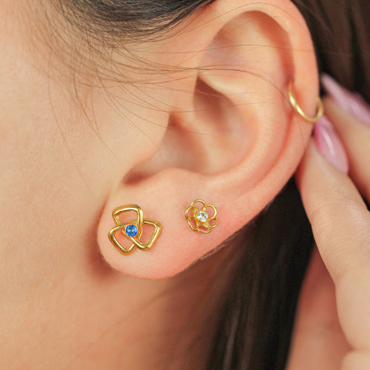 Oreja de mujer con topito en forma de triángulo en espiral en oro amarillo de 18 quilates con cristal de color azul en el centro, hechos en Joyería Caracas.