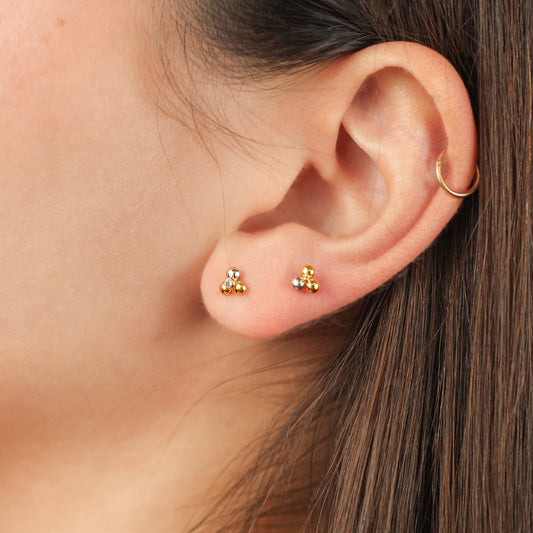 Oreja de mujer con topito en forma de flor de loto en oro blanco, rosa y amarillo de 18 quilates con cristal de color blanco en el centro, hechos en Joyería Caracas.