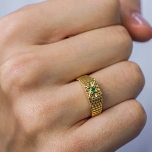 Mano de hombre con anillo en oro amarillo de 18 quilates con piedra esmeralda de color verde en el centro, hecho en Joyería Caracas.