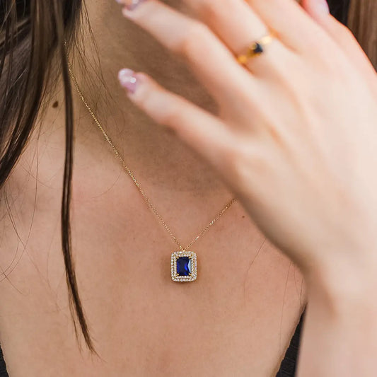 Cuello de mujer usando gargantilla con dije en oro amarillo de 18 quilates con cristal cuadrado de color azul en el centro con cristales de color blanco alrededor, hecho en Joyería Caracas.