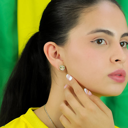 Mujer luciendo en su oreja topito en forma de leopardo en oro amarillo de 18 quilates, el cual también tiene cristales de color verde en los ojos y de color blanco a su alrededor.