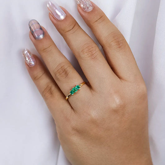 Mano de mujer con anillo en oro amarillo de 18 quilates y 3 esmeraldas en corte baguette, hecho en Joyería Caracas.