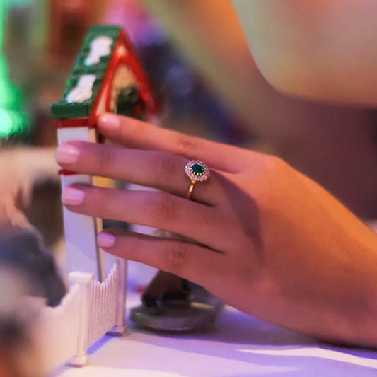 Mano de mujer con anillo en oro amarillo de 18 quilates con esmeralda en el centro y diamantes alrededor del anillo, hecho en Joyería Caracas.