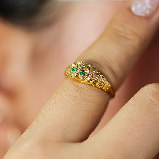 Mano de mujer con anillo en forma de Búho en oro amarillo de 18 quilates y 2 cristales de color verde, hecho en Joyería Caracas.