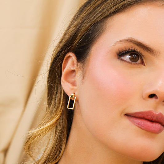 Oreja de mujer con arete en forma de rectángulo fabricado en oro amarillo de 18 quilates de Joyería Caracas.