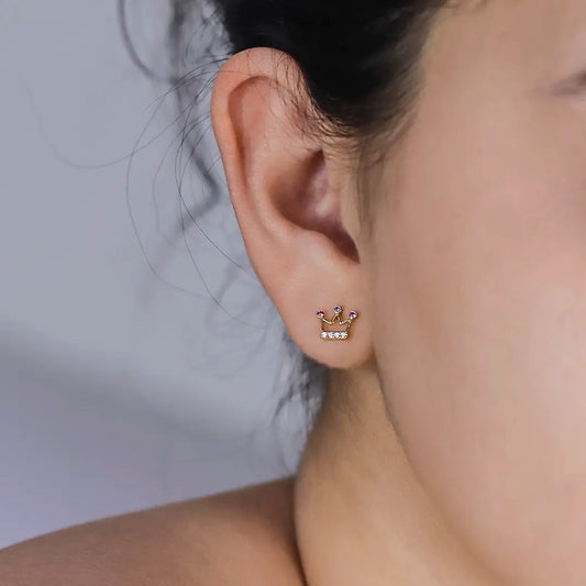 Oreja de mujer con topito en forma de corona en oro amarillo de 18 quilates, 3 cristales de color rojo y 4 cristales de color blanco, hecho en Joyería Caracas.