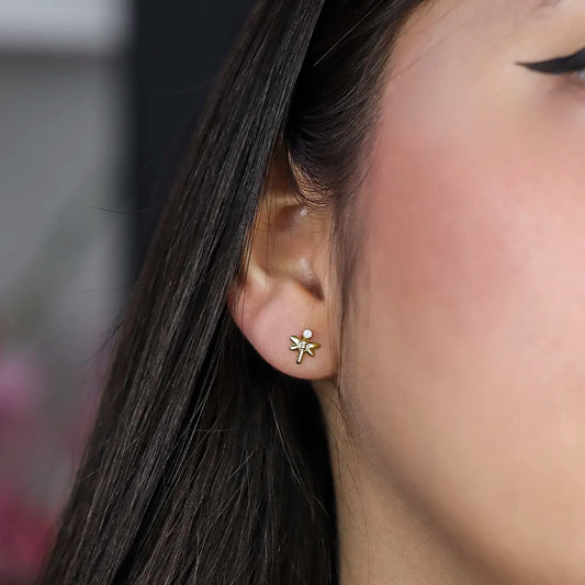 Oreja de mujer con topito en forma de libélula en oro amarillo de 18 quilates con cristal de color blanco, hechos en Joyería Caracas.