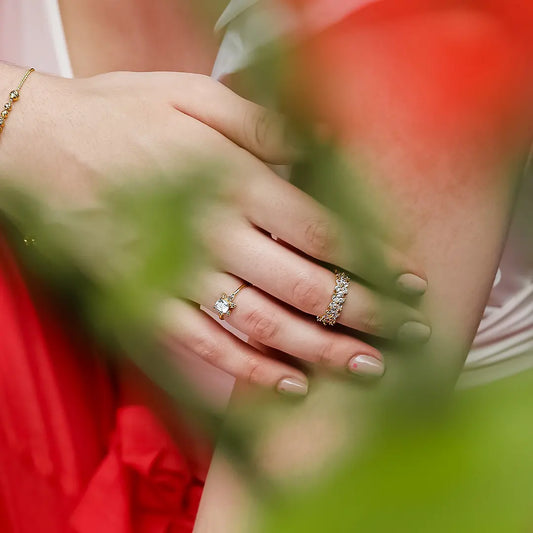 Mano de mujer con anillo en oro amarillo en forma de flor con cristales de color blanco, hecho en Joyería Caracas.