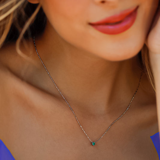 Cuello de mujer con gargantilla en oro blanco de 18 quilates con piedra esmeralda de color verde, hecho en Joyería Caracas.