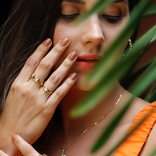 Mano de mujer con anillo en forma de serpiente en oro amarillo de 18 quilates con cristal de color rojo, hecho en Joyería Caracas.
