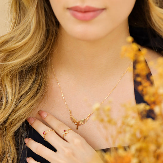 Mujer usando gargantilla de 2 alas abierta con una cruz en el medio en oro amarillo de 18 quilates de Joyería Caracas.