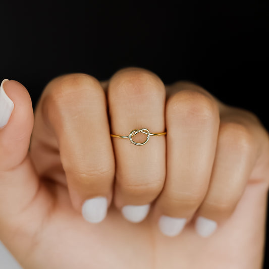 Mano de mujer con anillo en forma de nudo en oro amarillo de 18 quilates, hecho en Joyería Caracas.