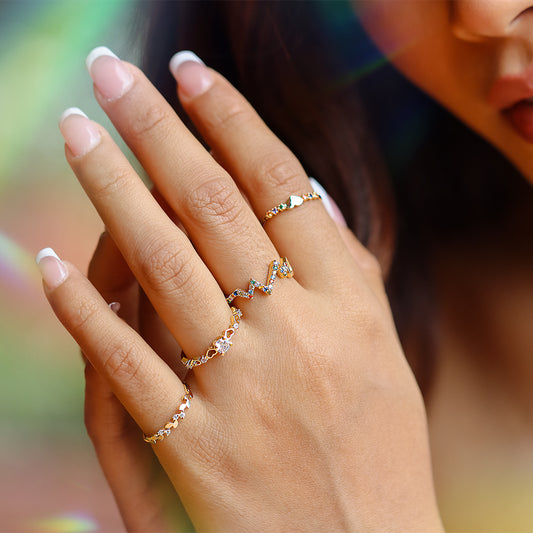 Mano de mujer usando anillo con formas de corazones alrededor en oro amarillo de 18 quilates, con diamantes de color blanco y piedra topacio en el centro, hecho en Joyería Caracas.