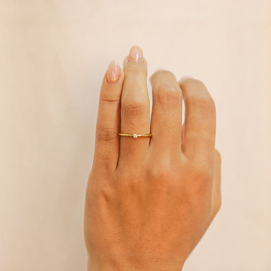 Mano de mujer con anillo en oro amarillo de 18 quilates con Diamante en el centro de color blanco.
