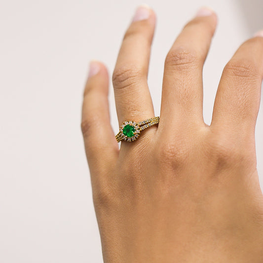 Mano de mujer con anillo en oro amarillo de 18 quilates con Esmeralda natural en el centro y Diamantes naturales alrededor y laterales.