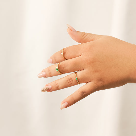 Mano de mujer con anillo en oro amarillo de 18 quilates, Esmeralda de color verde como piedra central y Diamantes en los laterales de color blanco, fabricado en Joyería Caracas.