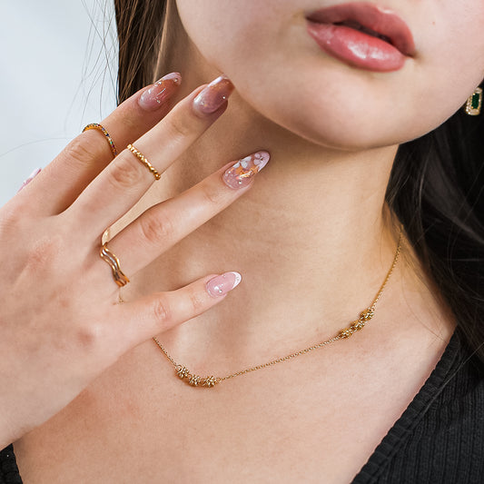 Mujer usando gargantilla con 3 accesorios en forma de flor en oro amarillo de 18 quilates.