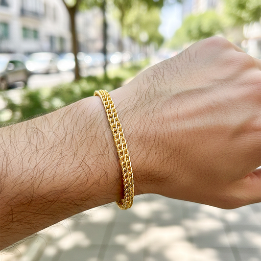 Mano de una modelo usando una pulsera en tejido saduza en oro amarillo de Joyería Caracas.